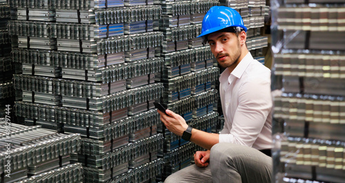 young hispanic male worker wearing safety hard hat helmet inspecting metal raw materials for roofing warehouse