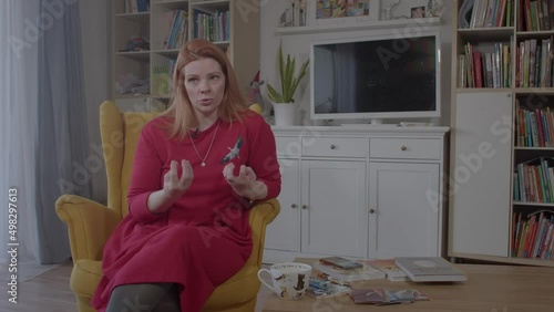 Woman speaks actively gesturing in home interiors. Give comments to the media on an important topic, express your opinion. 