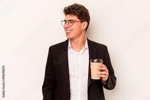 Young caucasian business man holding takeaway coffee isolated on white background looks aside smiling, cheerful and pleasant.