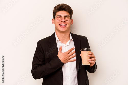 Young caucasian business man holding takeaway coffee isolated on white background laughs out loudly keeping hand on chest.