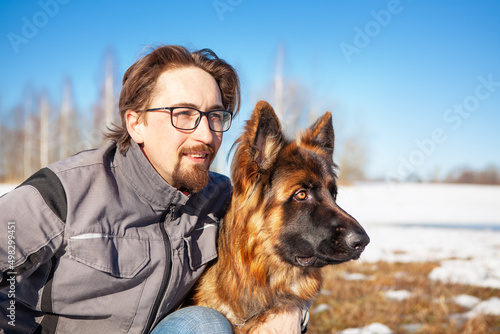 Portrait of a man with his German Shepherd dog in winter, against a blue sky. © наталья саксонова