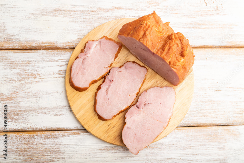 Smoked pork ham on cutting board on white wooden background. Top view, close up.