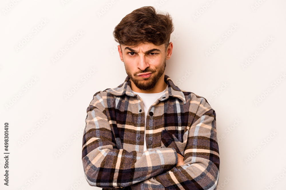 Fototapeta premium Young hispanic man isolated on white background frowning face in displeasure, keeps arms folded.