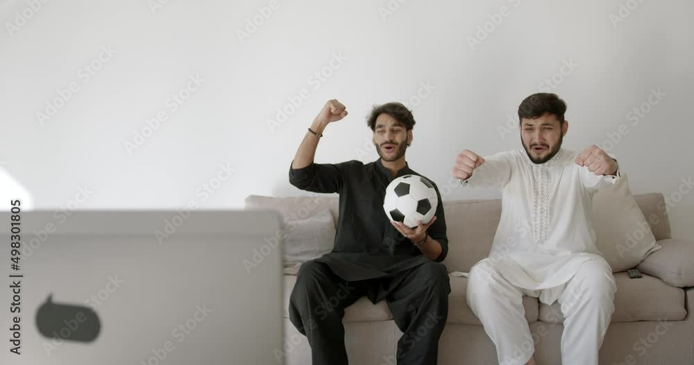 Two Indian men watch football in a modern room Two Indian men watch football in a modern room