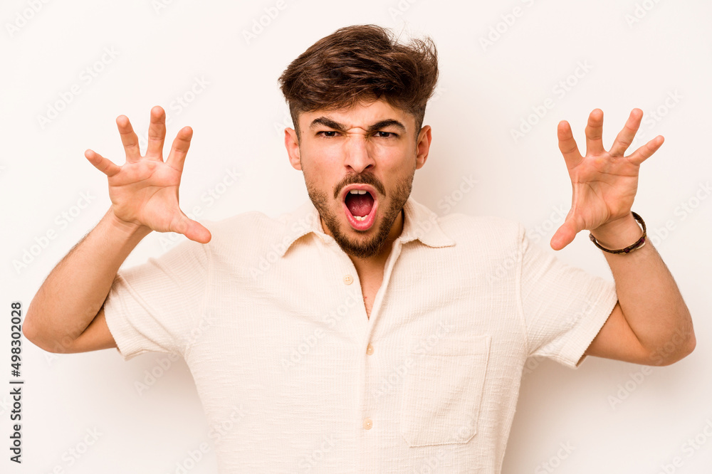 Young hispanic man isolated on white background showing claws imitating a cat, aggressive gesture. Young hispanic man isolated on white background showing claws imitating a cat, aggressive gesture.