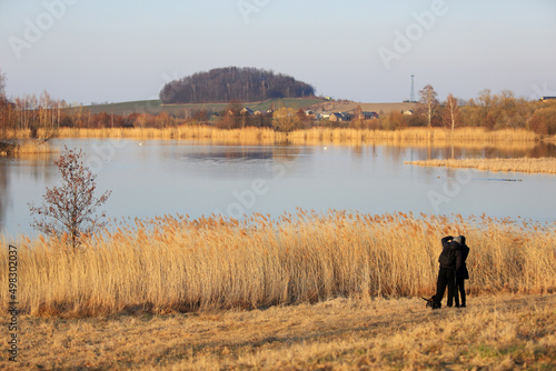 Para młodych ludzi z psem na spacerze brzegiem jeziora. 