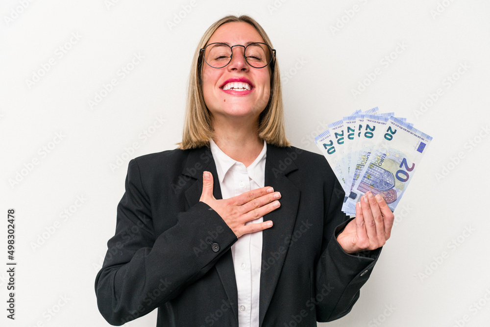 Young business caucasian woman holding banknotes isolated on white background laughs out loudly keeping hand on chest. Young business caucasian woman holding banknotes isolated on white background laughs out loudly keeping hand on chest.
