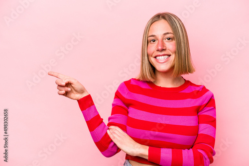 Young caucasian woman isolated on pink background smiling cheerfully pointing with forefinger away.