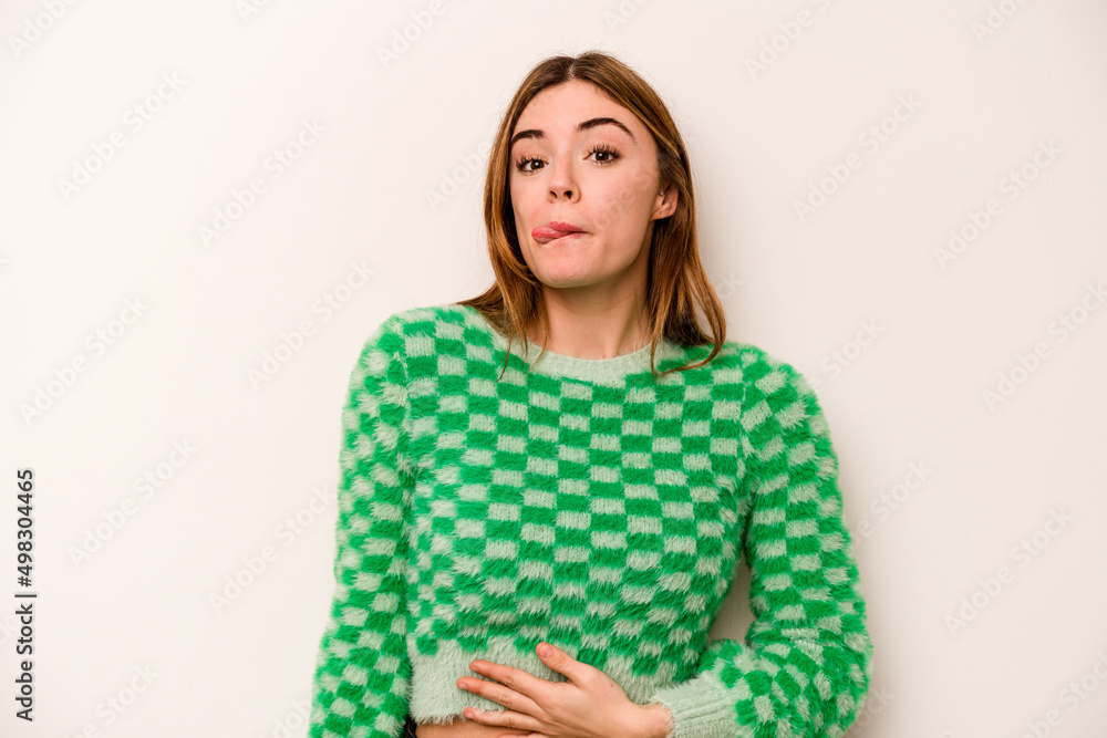 Young caucasian woman isolated on white background touches tummy, smiles gently, eating and satisfaction concept.