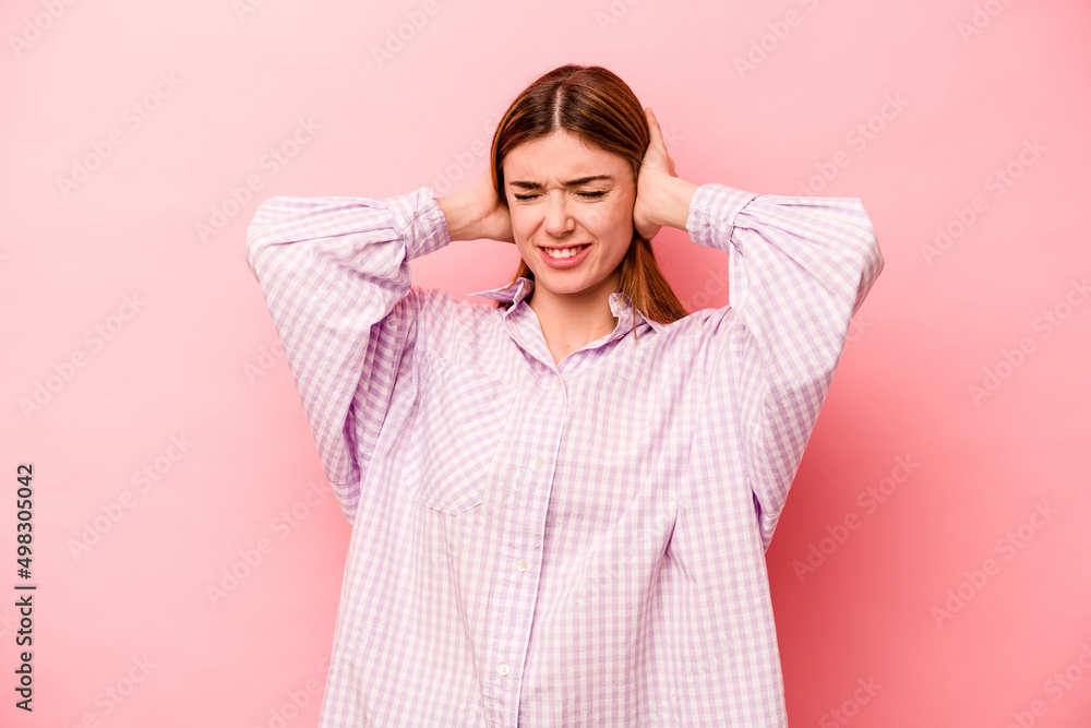 Young caucasian woman isolated on pink background covering ears with hands. Young caucasian woman isolated on pink background covering ears with hands.