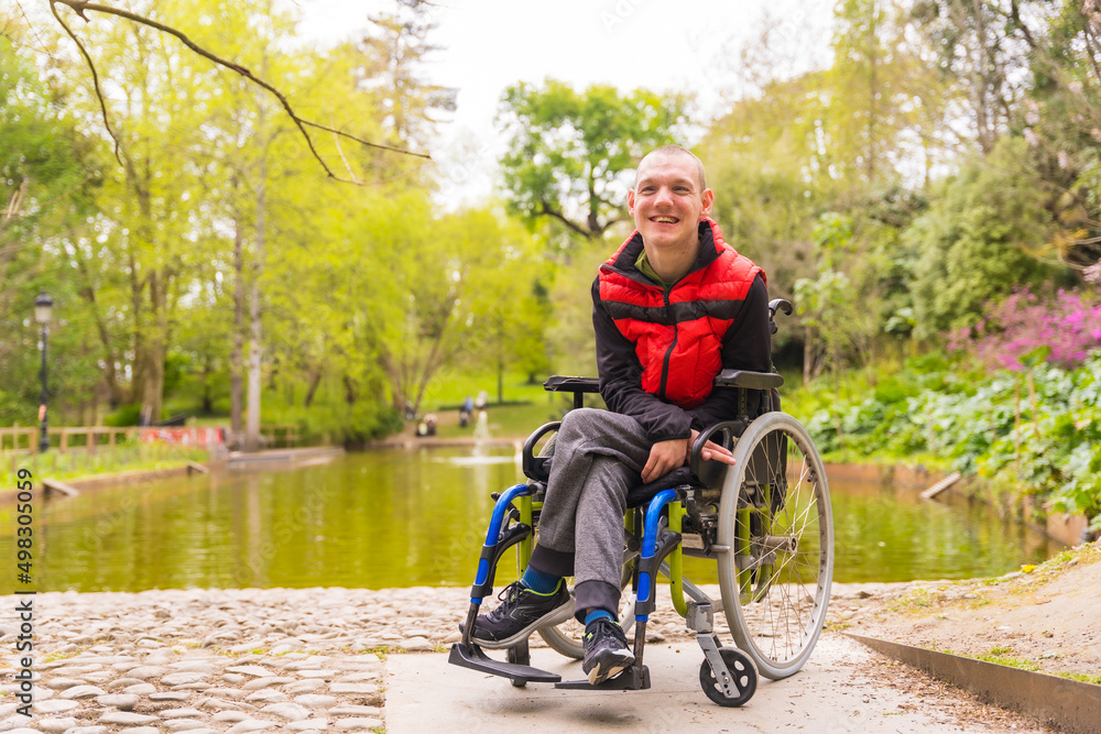Portrait of a person with a disability in a public park in the city. Sitting in the wheelchair in a public park in the city. Sitting in the wheelchair