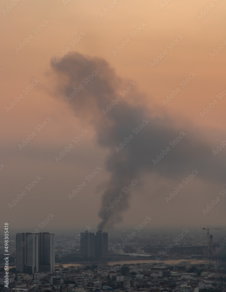 Bangkok, Thailand - 08 Apr, 2022 : Plume of black smoke clouds from Burnt buildings on fire at some area in the bangkok city in the evening. Fire disaster accident, Selective focus.