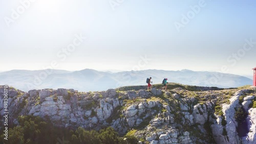 4K dynamic aerial drone footage of a backpackers couple with backpacks and trekking poles hiking by the Dinaric Alps mountain Range. Sinjal or Dinara (1831 m) mountain - the highest point of Croatia. photo