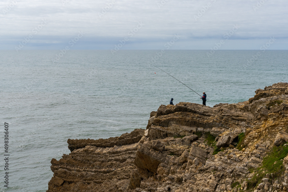 fisherman fishing from a rocky cliff on the wild Atlantic coast of northern Portugal