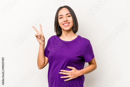Young hispanic pregnant woman isolated on white background joyful and carefree showing a peace symbol with fingers.
