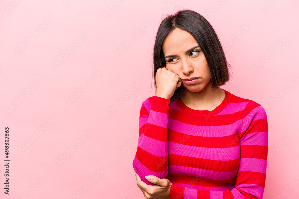 Young hispanic woman isolated on pink background who feels sad and pensive, looking at copy space. Young hispanic woman isolated on pink background who feels sad and pensive, looking at copy space.