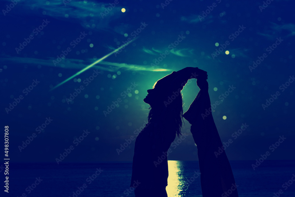 Woman enjoying under starry, Moonlit night above the ocean waters.