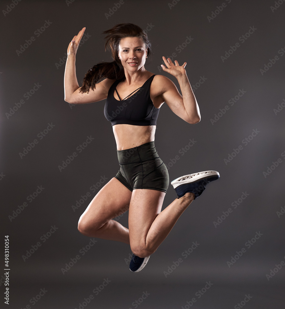 Woman jumping high isolated on gray