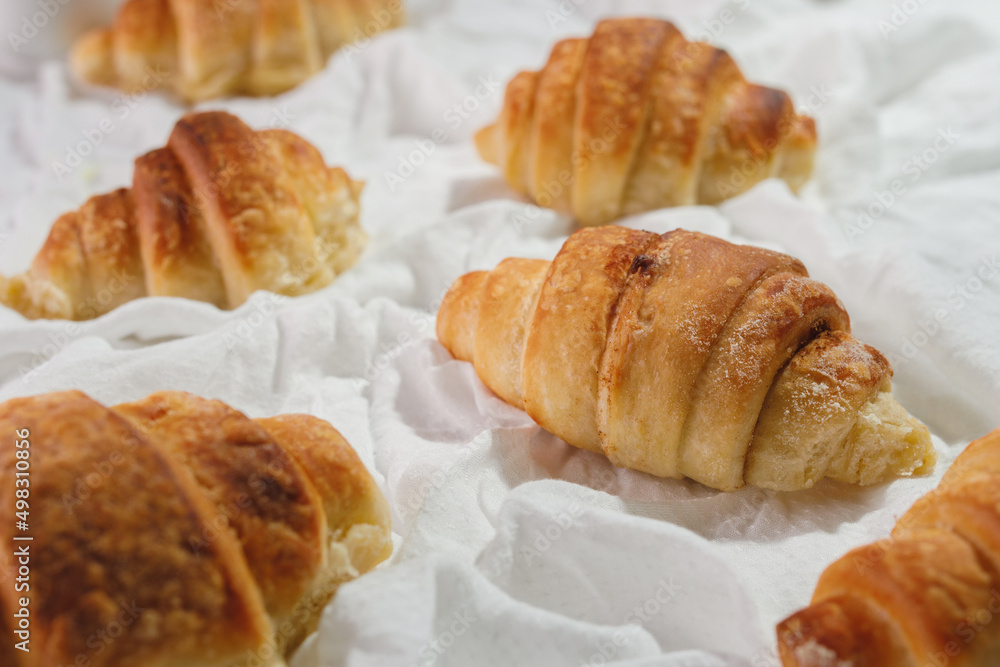 homemade croissants on a white textile background.
