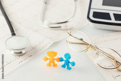 Family healthcare, medicine and insurance concept. Family figures, cardiograms, tonometer, stethoscope and glasses on a white doctor desk. Medical worktable. Soft image and soft focus style