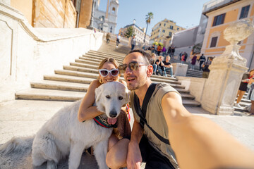 Man and woman taking selfie photo with a dog on backgorund of Spanish steps. Concept of happy vacations in Rome