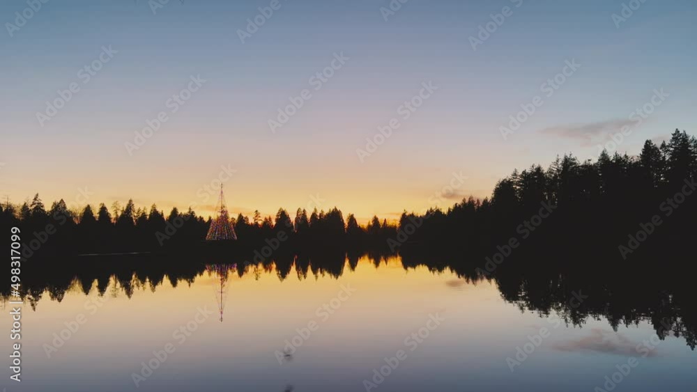 Beautiful view of Lost Lagoon Lake at sunset with decorated christmas tree in the background Beautiful view of Lost Lagoon Lake at sunset with decorated christmas tree in the background