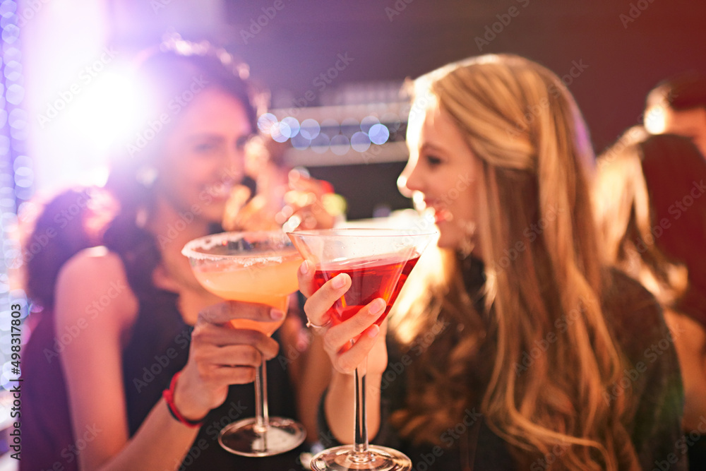 Clink before you drink. Shot of two young women drinking cocktails at a party. Clink before you drink. Shot of two young women drinking cocktails at a party.