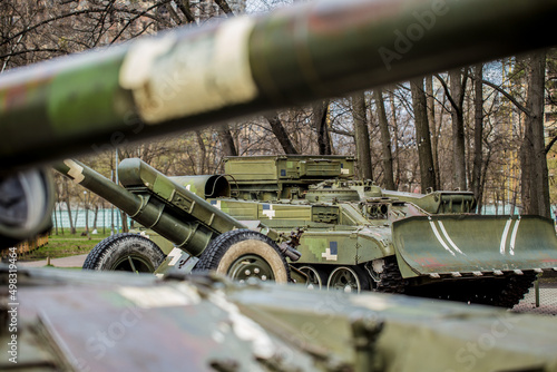 Tank and howitzer stand on the street in Ukraine. In the Kiev park there is a gun and a green tank.