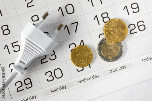 AC power cable with EU power plug (type C, 2 pins) and several euro coins and Euro cents on calendar. Lack of money to pay for electricity, last money, expensive electricity concept photo