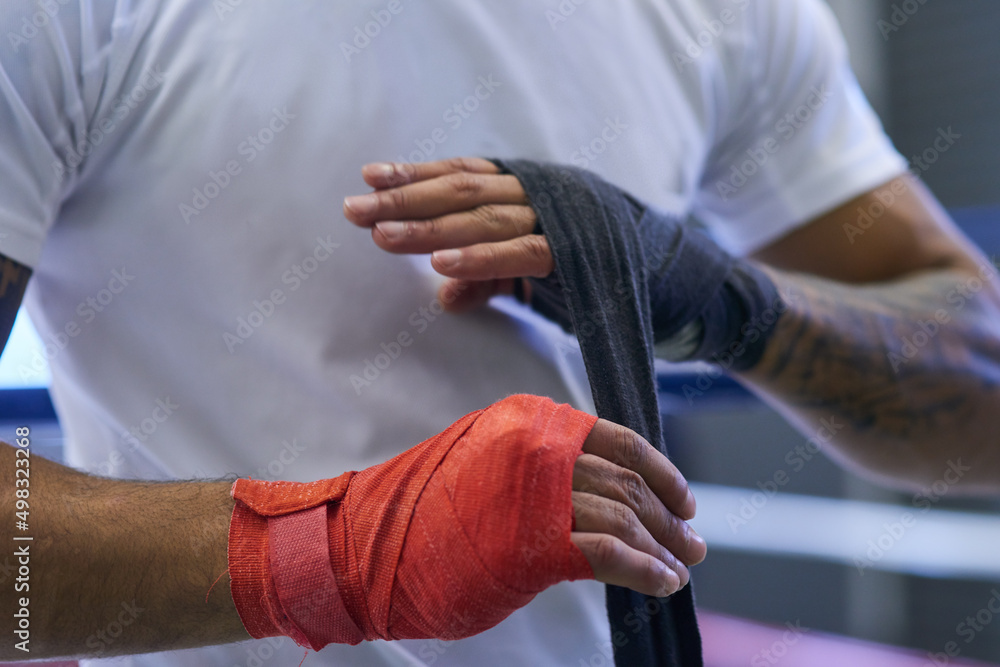 Dont underestimate the importance of hand wrap. Shot of an unrecognizable man strapping his hands and wrists in he boxing gym.