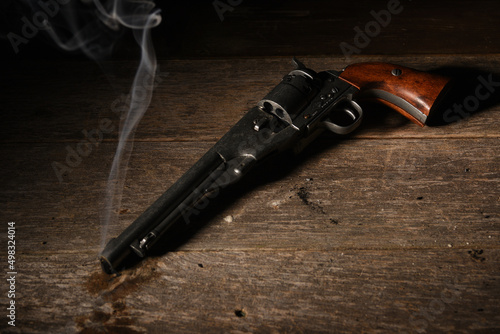 old west gun lays on floor after gunfight with smoke coming from barrel on saloon floor