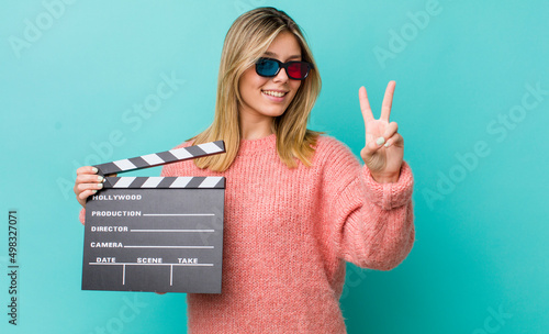 pretty blonde woman smiling and looking friendly, showing number two. cinema concept photo