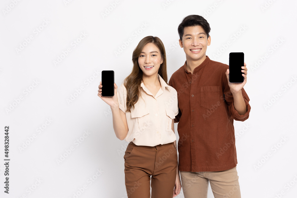 Portrait of young smiling Asian couple holding and showing mobile phone application isolated on white background, Asian Thai model Portrait of young smiling Asian couple holding and showing mobile phone application isolated on white background, Asian Thai model