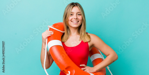 pretty blonde woman smiling happily with a hand on hip and confident. lifeguard concept