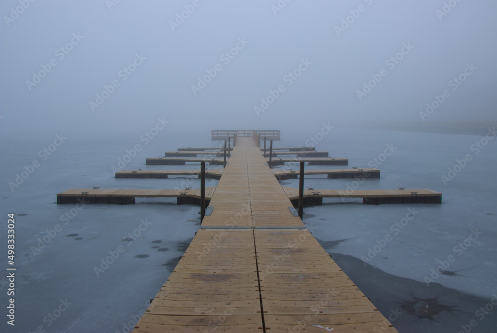 pier on frozen lake with fog background