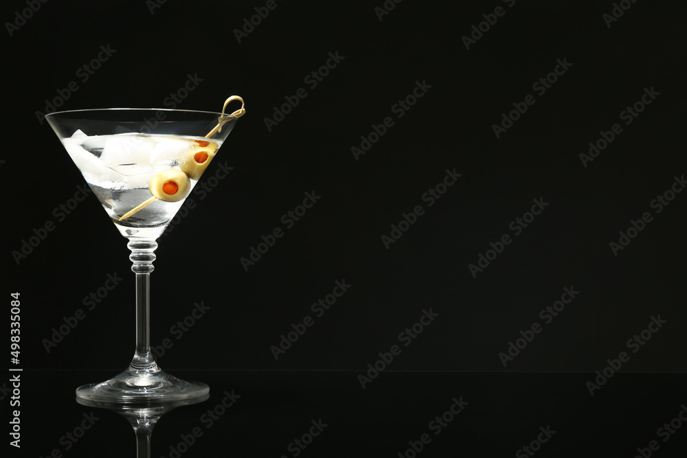Martini cocktail with ice and olives on dark background. Space for text