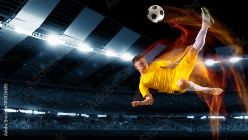 Active professional soccer, football player kick the ball in jump at dark night stadium with flashlights. Sport, competition, championship