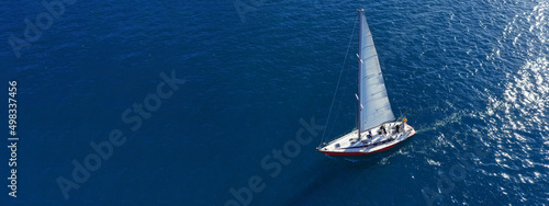 Aerial drone ultra wide panoramic photo with copy space of beautiful sail boat with white sails cruising deep blue Aegean sea