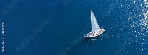 Aerial drone ultra wide panoramic photo with copy space of beautiful sail boat with white sails cruising deep blue Aegean sea