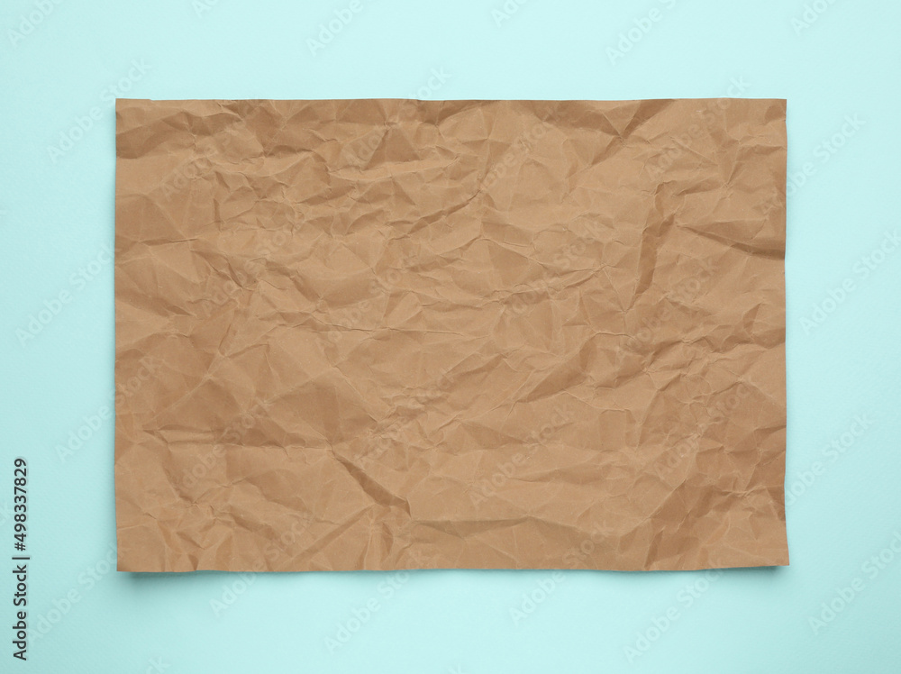 Sheet of crumpled brown paper on light blue background, top view Sheet of crumpled brown paper on light blue background, top view