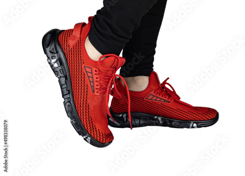 legs in black jeans and red sneakers, isolated on a white background.