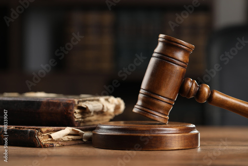 Wooden gavel and antique books on table, closeup
