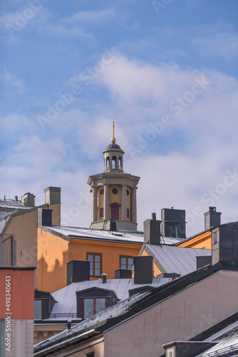 Dorms, chimneys and towers with black tin roofs on old 1700s buildings a snowy spring day in Stockholm