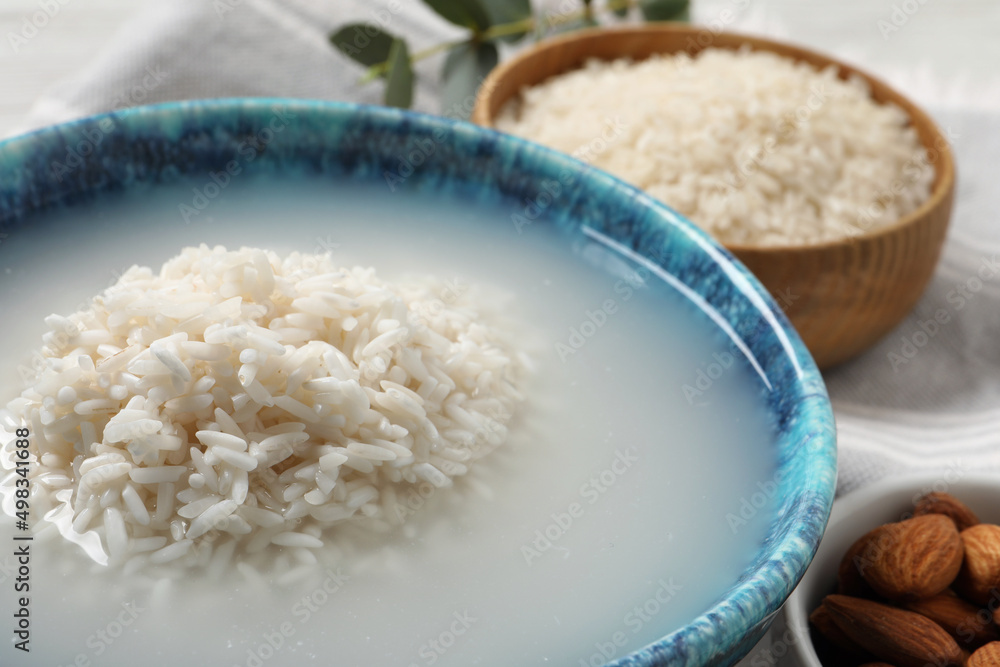 Bowl with rice soaked in water on table, closeup