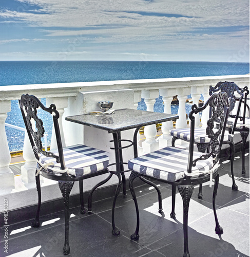 What a view. Tables and chairs on the balcony of a seaside restaurant. photo