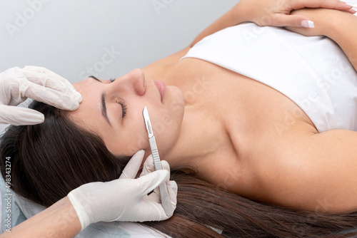 young woman in a beauty center performing a beauty treatment for the skin of the face with the dermaplaning technique