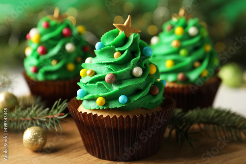 Tasty Christmas cupcakes on wooden board, closeup