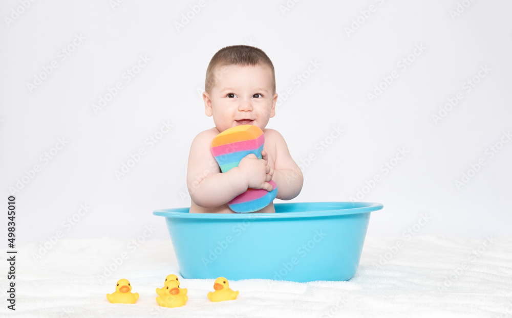 Bathing the baby in bath with yellow rubber ducks, Baby sitting in the bath and looking at the camera. A lot of bubbles flying in the bathroom. Boy takes bath. Bathing the baby in bath with yellow rubber ducks, Baby sitting in the bath and looking at the camera. A lot of bubbles flying in the bathroom. Boy takes bath.