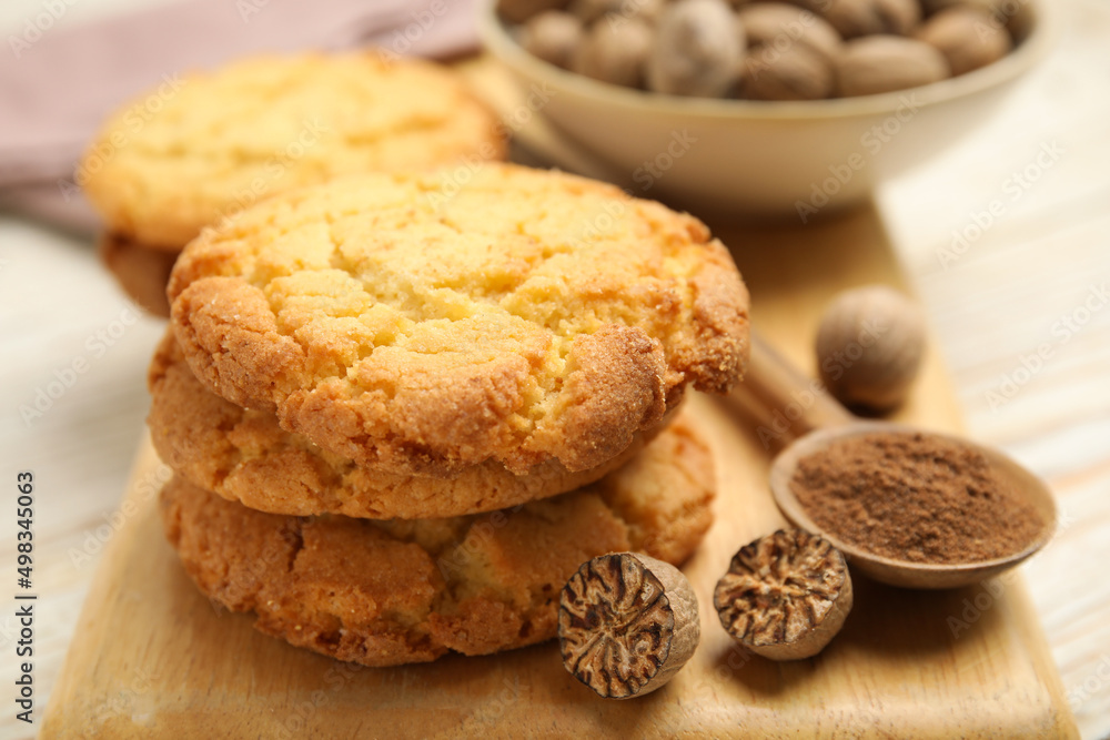 Nutmeg powder, seeds and tasty cookies on wooden board, closeup Nutmeg powder, seeds and tasty cookies on wooden board, closeup