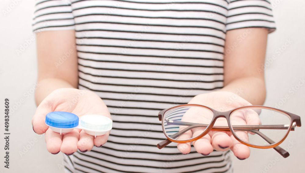 Obraz premium Woman in black-white t-shirt keep contact lens case and glasses. Concept of choice the way vision correction 